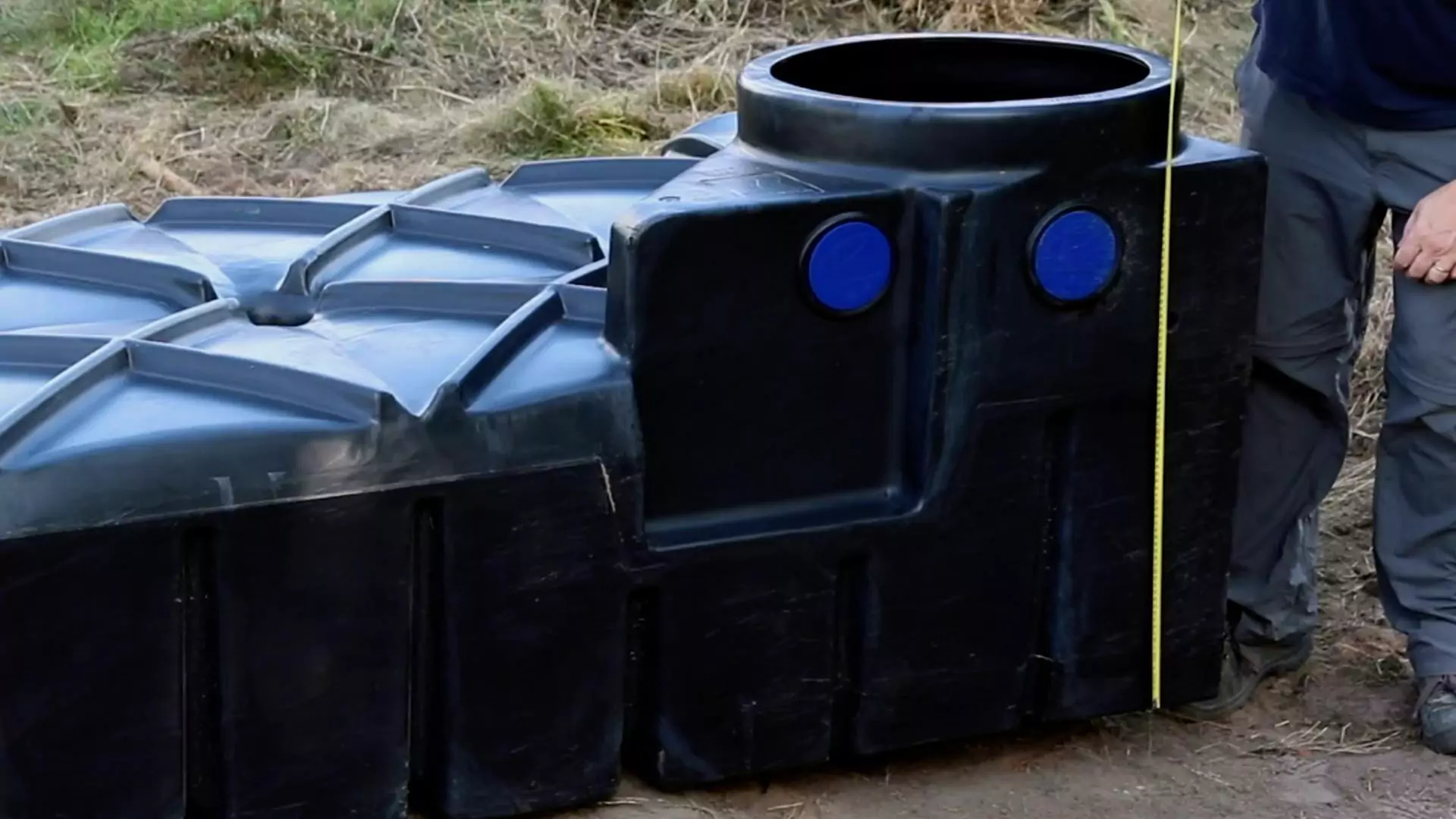 Mètre ruban déplié contre une citerne plate noire, au niveau de son trou d’homme