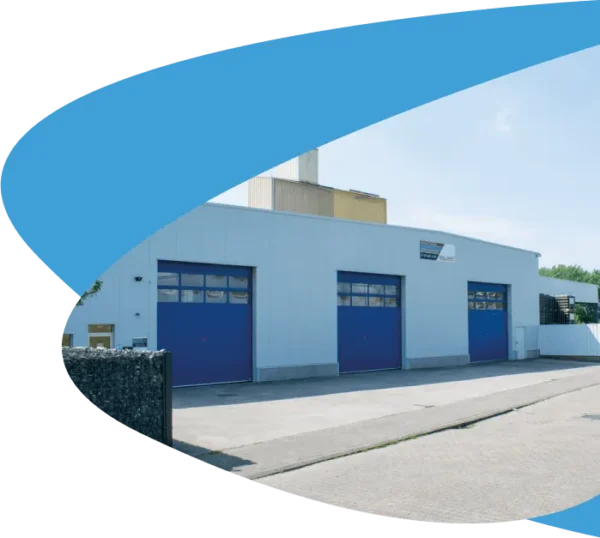 Bâtiment gris clair du dépôt Bollaert à Wetteren, avec trois grandes portes bleues et une cour pavée devant